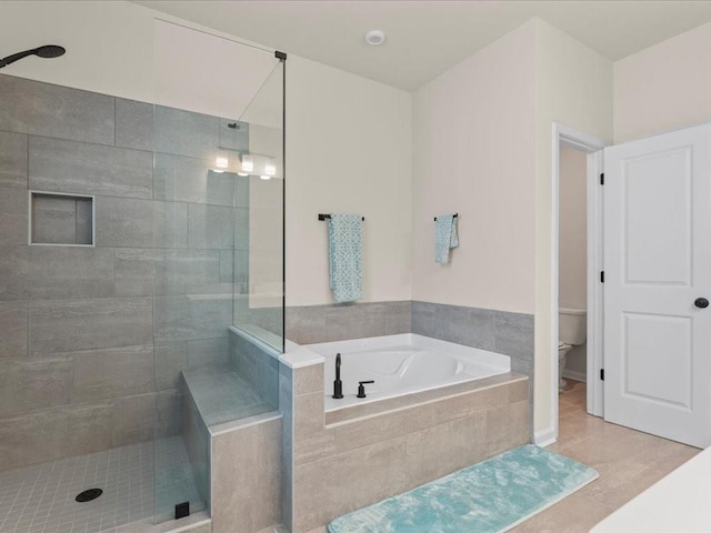 full bath featuring a garden tub, a tile shower, and toilet