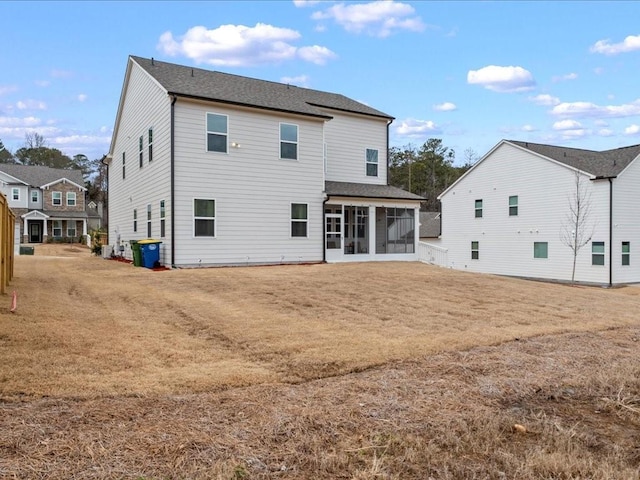 rear view of property with a yard, a sunroom, and fence