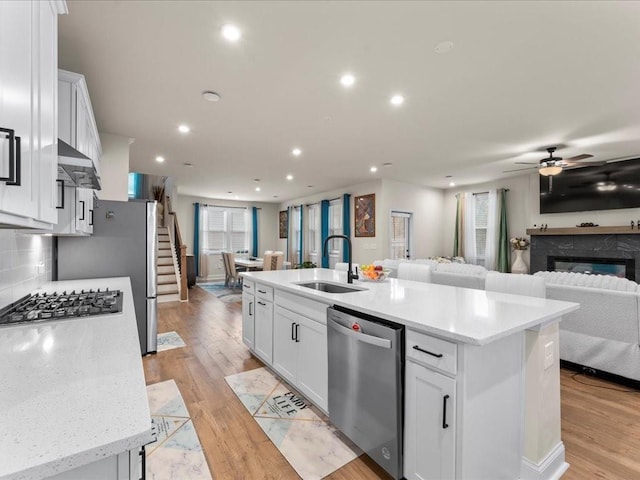 kitchen featuring a center island with sink, appliances with stainless steel finishes, open floor plan, white cabinetry, and a sink