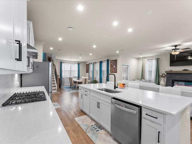 kitchen featuring stainless steel appliances, open floor plan, a kitchen island with sink, and a sink