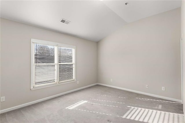 empty room featuring visible vents, carpet flooring, lofted ceiling, and baseboards