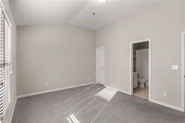 unfurnished bedroom with baseboards, lofted ceiling, carpet floors, and ensuite bath