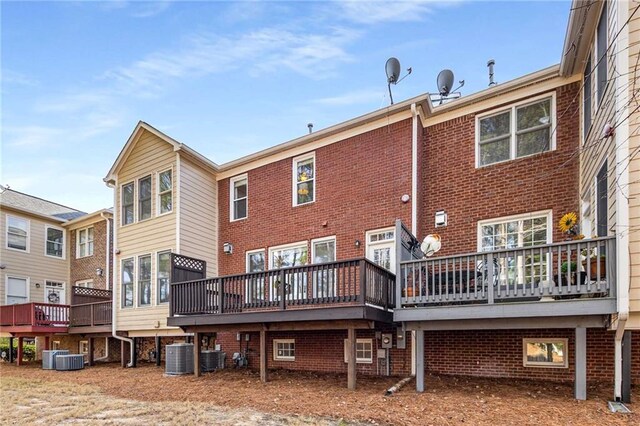rear view of property with brick siding, central air condition unit, and a wooden deck
