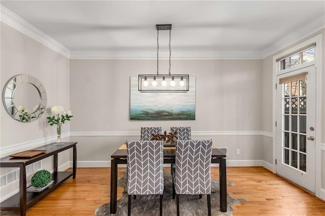 dining space with crown molding, baseboards, and wood finished floors