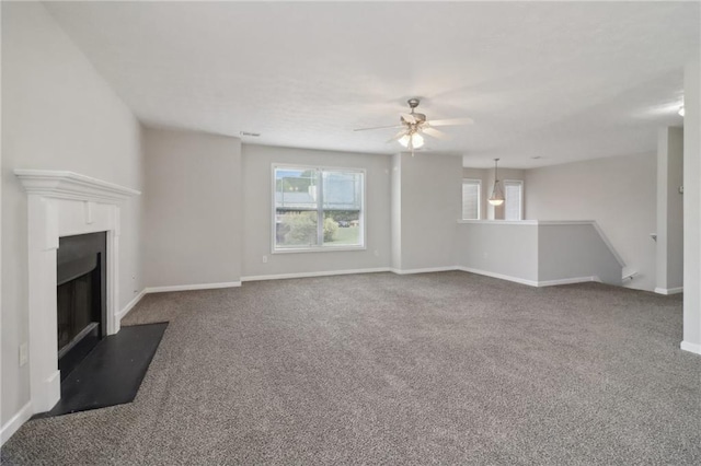 unfurnished living room with a fireplace with flush hearth, carpet flooring, plenty of natural light, and a ceiling fan