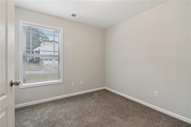 empty room featuring visible vents, baseboards, and carpet