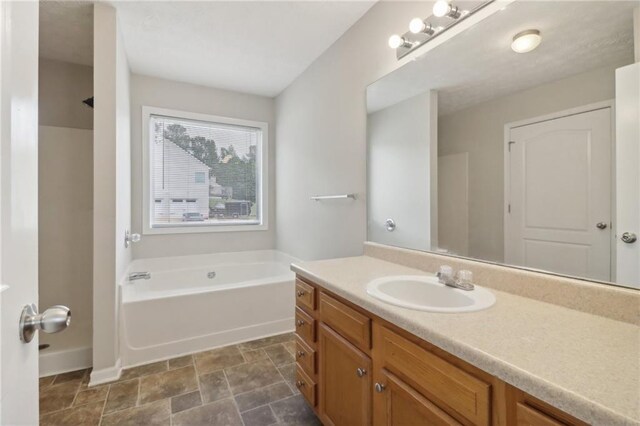 bathroom featuring stone finish floor, vanity, and a garden tub