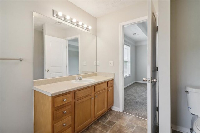 bathroom with stone finish flooring, toilet, vanity, and baseboards
