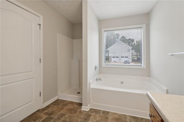 bathroom with vanity, a bath, baseboards, and a stall shower