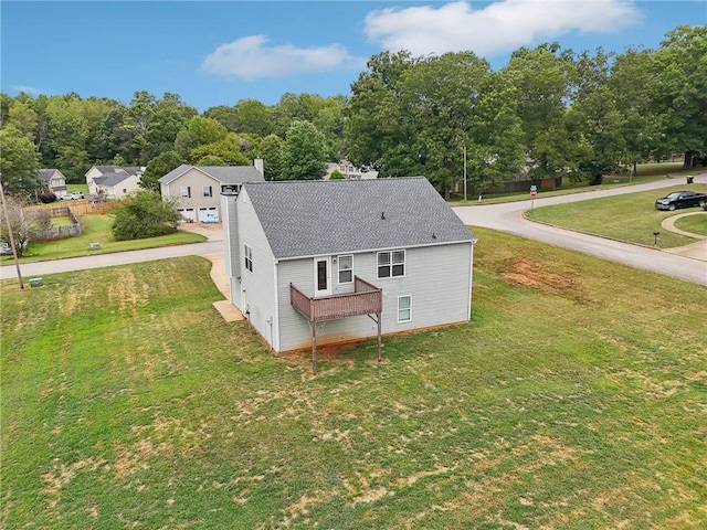 rear view of property featuring a lawn, a chimney, and a shingled roof