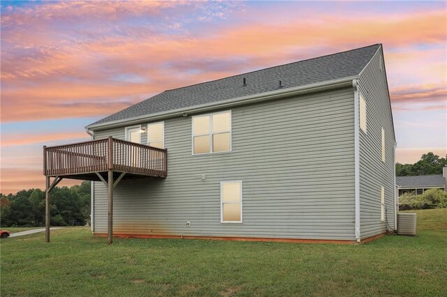 rear view of house featuring a lawn and a deck