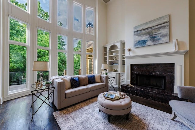 living area with plenty of natural light, a high ceiling, wood finished floors, and a high end fireplace