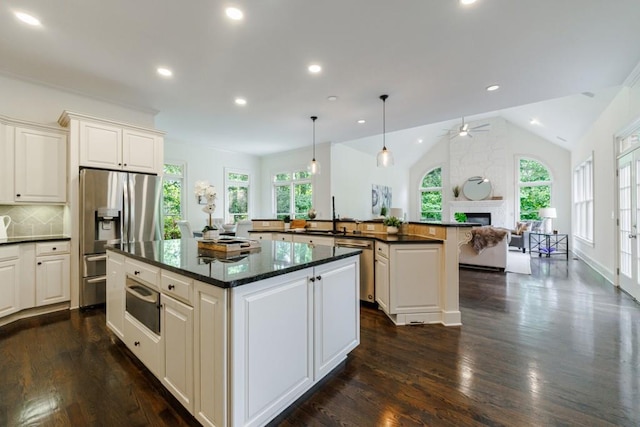 kitchen with lofted ceiling, stainless steel appliances, open floor plan, a center island, and a warming drawer