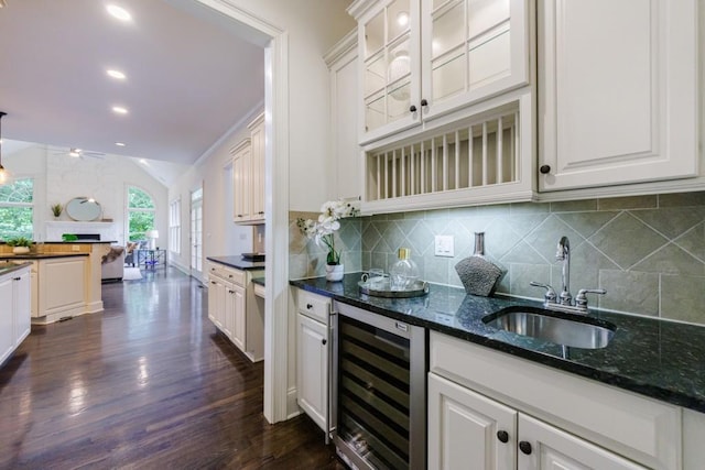 kitchen featuring tasteful backsplash, beverage cooler, dark wood-style flooring, vaulted ceiling, and a sink