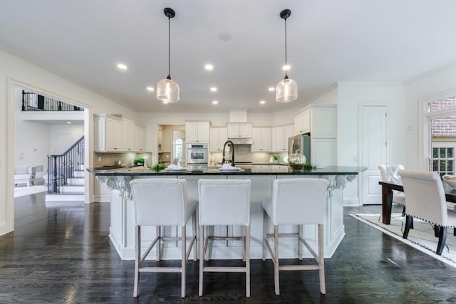 kitchen with stainless steel appliances, dark countertops, a sink, and a kitchen breakfast bar