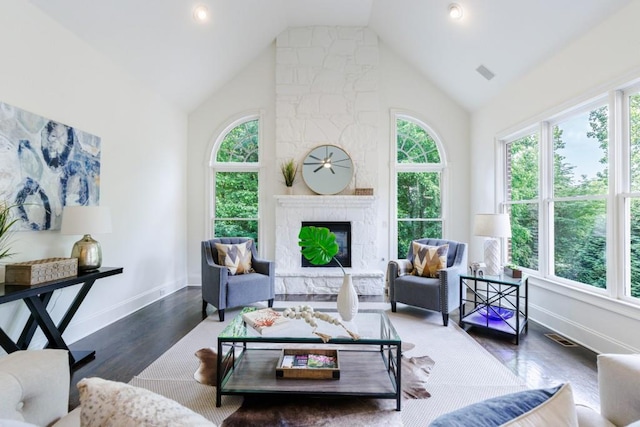 living area with a large fireplace, high vaulted ceiling, wood finished floors, and visible vents