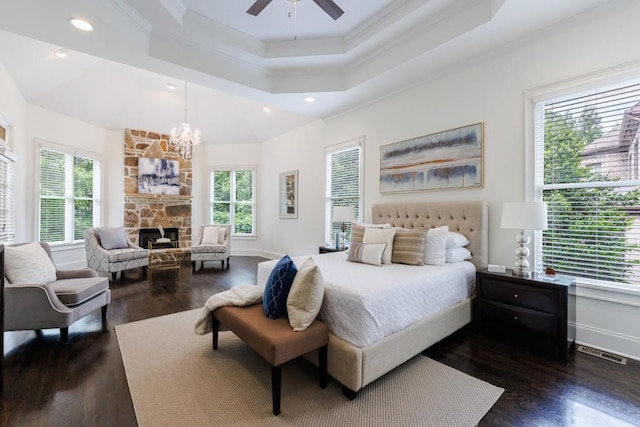 bedroom with crown molding, a fireplace, a raised ceiling, and dark wood-type flooring