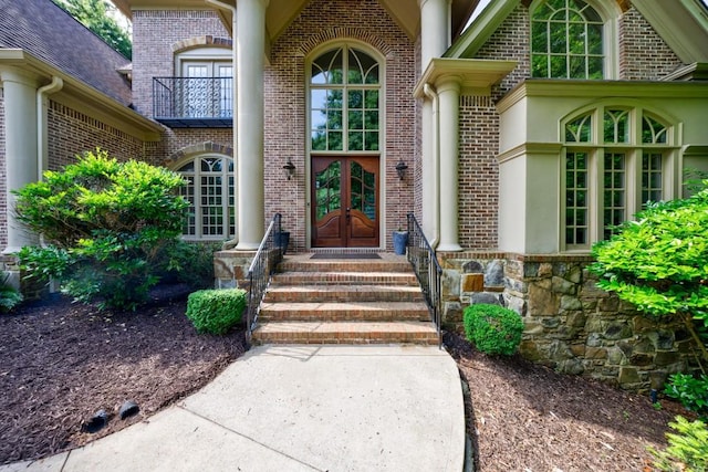 doorway to property featuring french doors, a balcony, and brick siding