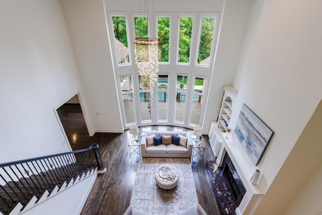 living room featuring baseboards, stairway, a high ceiling, and wood finished floors