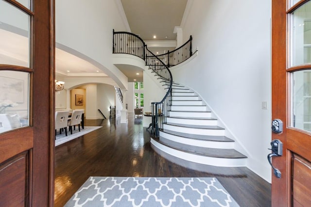 entrance foyer featuring ornamental molding, stairway, a towering ceiling, and wood finished floors