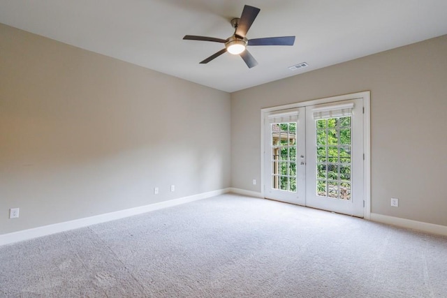 carpeted spare room featuring baseboards, visible vents, a ceiling fan, and french doors