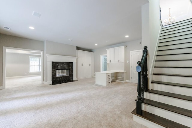 unfurnished living room featuring recessed lighting, light carpet, a premium fireplace, visible vents, and stairs