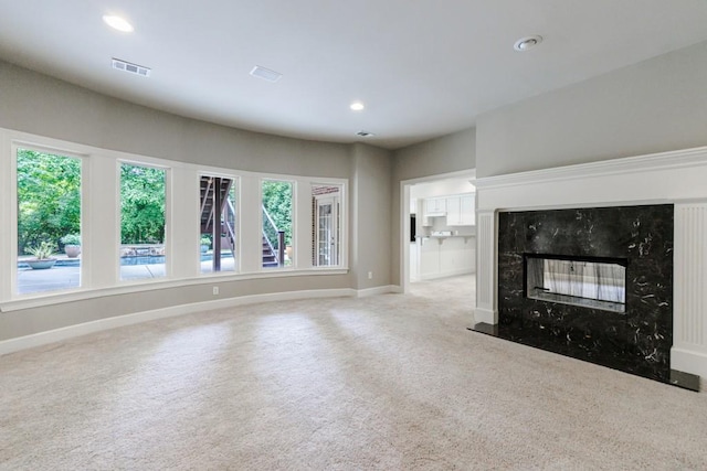 unfurnished living room featuring visible vents, baseboards, a high end fireplace, carpet flooring, and recessed lighting