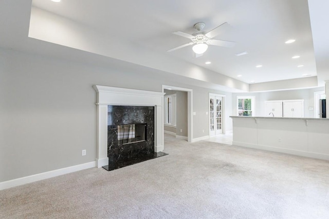 unfurnished living room with light carpet, a fireplace, baseboards, and recessed lighting