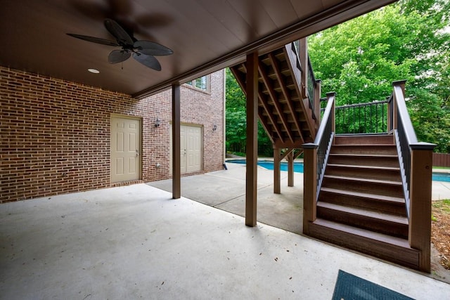 view of patio / terrace featuring an outdoor pool, ceiling fan, and stairway