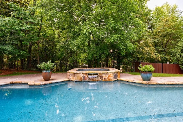 view of swimming pool featuring a pool with connected hot tub and fence