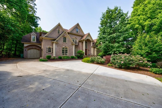 view of front of property featuring an attached garage, concrete driveway, and brick siding