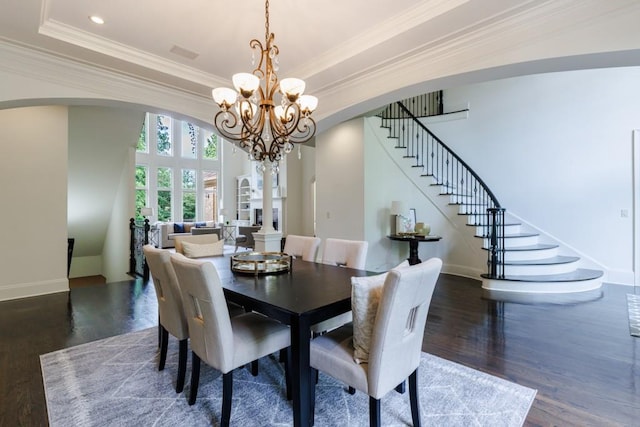 dining area featuring arched walkways, a raised ceiling, ornamental molding, wood finished floors, and stairs