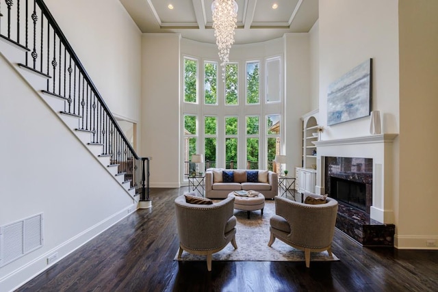 living room with a high ceiling, coffered ceiling, wood finished floors, visible vents, and baseboards