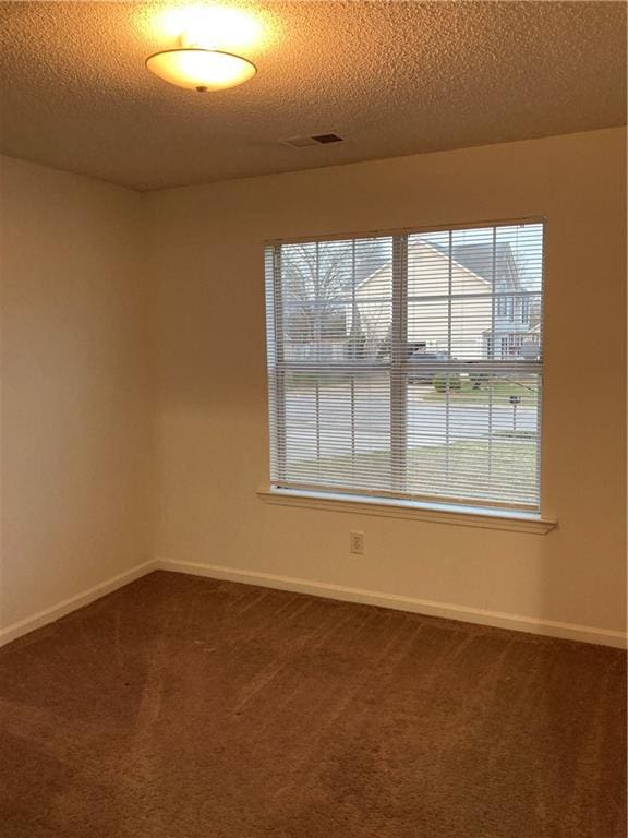 carpeted spare room featuring a textured ceiling