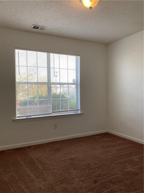 carpeted spare room featuring a textured ceiling