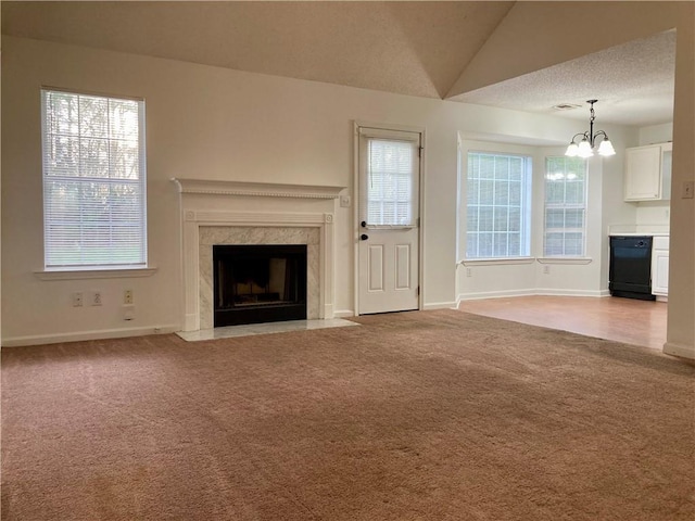 unfurnished living room with a wealth of natural light, a high end fireplace, light colored carpet, and lofted ceiling