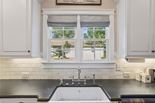 kitchen featuring plenty of natural light, sink, white cabinets, and backsplash