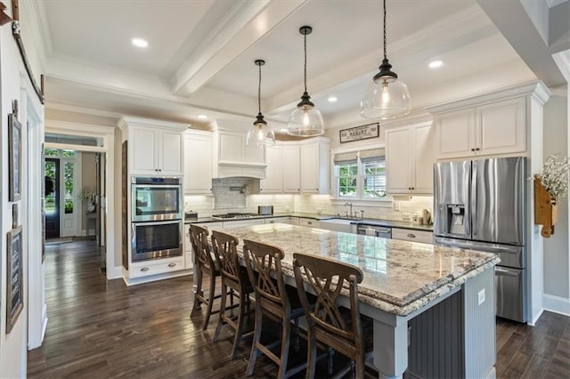 kitchen with a kitchen island, appliances with stainless steel finishes, hanging light fixtures, and white cabinets