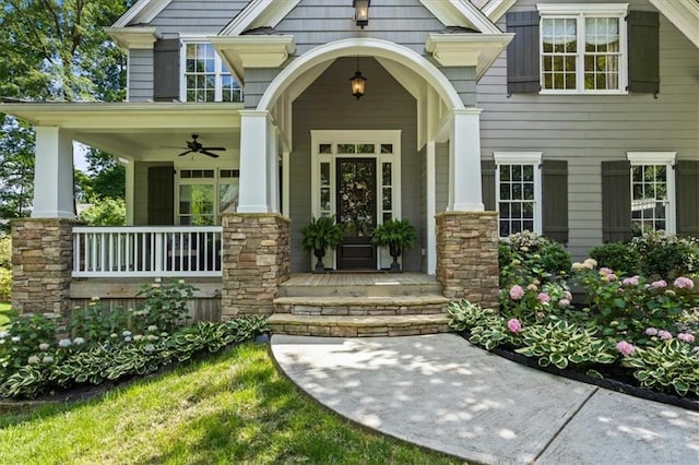 view of exterior entry with ceiling fan and a porch