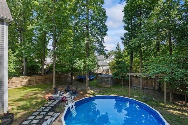 view of swimming pool featuring a trampoline and a fire pit