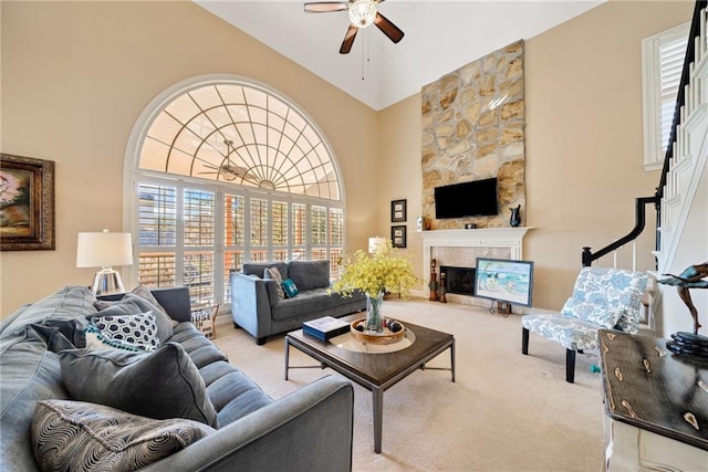 living room featuring light carpet, a stone fireplace, and ceiling fan