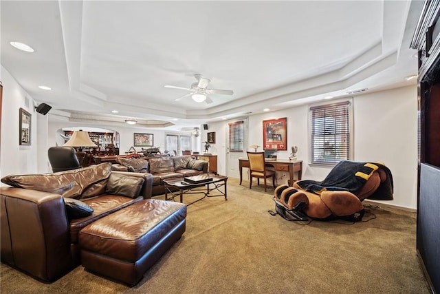 living room featuring ceiling fan, carpet flooring, and a tray ceiling