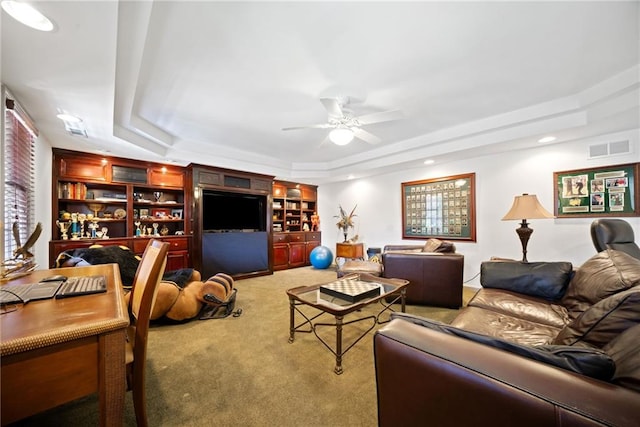 living room featuring a raised ceiling, carpet floors, and ceiling fan