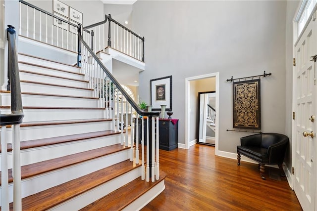 stairs with hardwood / wood-style floors and a high ceiling