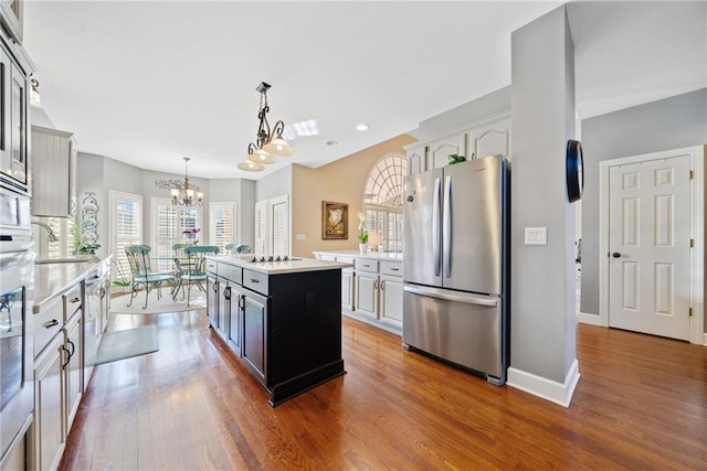 kitchen with white cabinetry, a kitchen island, stainless steel refrigerator, and decorative light fixtures