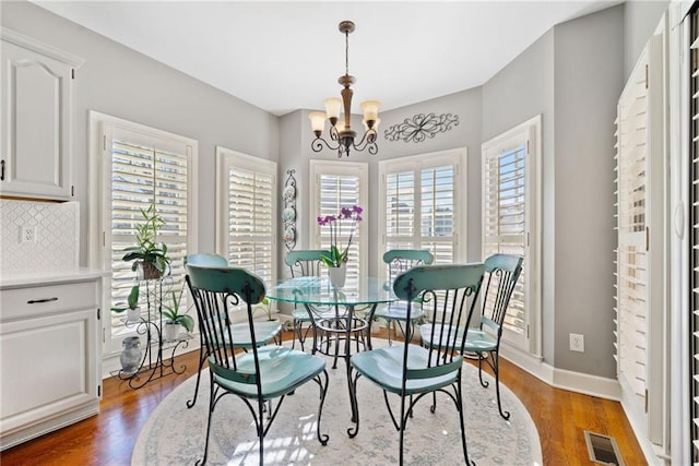 dining area featuring a notable chandelier and dark wood-type flooring