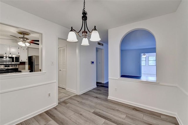 unfurnished dining area with light hardwood / wood-style floors and ceiling fan with notable chandelier