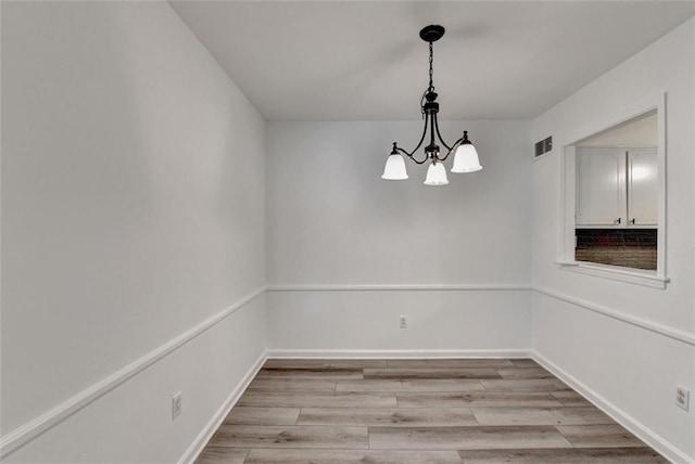 unfurnished room with light hardwood / wood-style floors and a notable chandelier