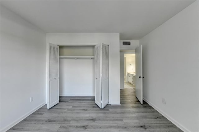 unfurnished bedroom with light wood-type flooring and a closet