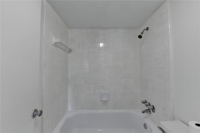 bathroom with toilet and tiled shower / bath